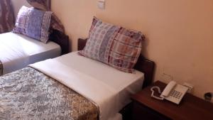 Cette petite chambre comprend deux lits et un téléphone. dans l'établissement 70 Dereja Hotel, à Addis-Abeba