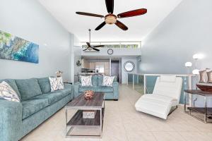 uma sala de estar com um sofá azul e uma ventoinha de tecto em Ocean View Penthouse with pool, beachfront complex apts em Río Grande