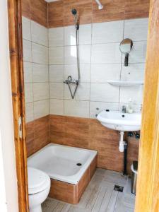 a bathroom with a tub and a toilet and a sink at Köröstorok Apartmanok in Csongrád