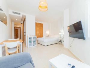 a white room with a bed and a tv at Nuevo con Piscina y Parking en la Playa in Torre de Benagalbón