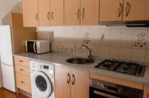 een keuken met een wastafel, een fornuis en een magnetron bij Maravilloso apartamento en el centro in Ceuta