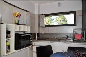 a kitchen with a microwave and a sink and a window at Complejo del Este in San Carlos de Bariloche