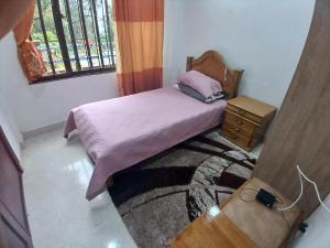 ein kleines Schlafzimmer mit einem Bett und einem Fenster in der Unterkunft Grernhouse in Manizales