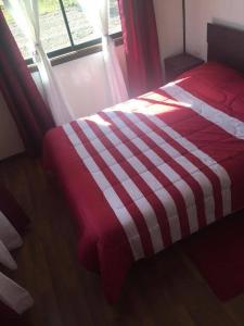 ein rotes und weißes Bett in einem Zimmer mit Fenster in der Unterkunft Cabañas Lanco in Panguipulli