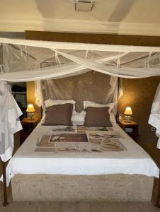 a bedroom with a canopy bed with white sheets and pillows at Superbe 2pieces avec climatisation in Fatick
