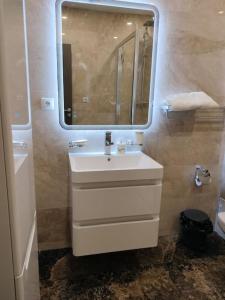 een badkamer met een witte wastafel en een spiegel bij Nina Studio Sibiu in Cisnădie