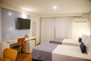 a hotel room with two beds and a desk at Bristol Jangada Fortaleza Meirelles in Fortaleza