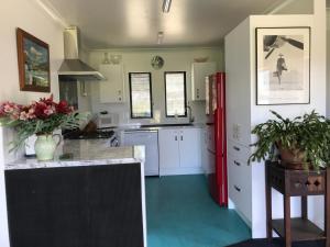 a kitchen with white cabinets and a red refrigerator at Woodbank Road Escape in Hanmer Springs
