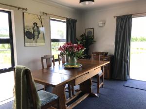 a dining room with a wooden table with flowers on it at Woodbank Road Escape in Hanmer Springs