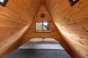 a bed in a wooden cabin with a window at Cabañitas del Bosque in Algarrobo