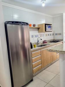 Il comprend une cuisine équipée d'un réfrigérateur en acier inoxydable. dans l'établissement Bem no CENTRO com cozinha completa, varanda e garagem, à Poços de Caldas