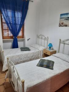 2 letti in una camera da letto con tende blu e finestra di Villetta Alessia a Marina di Mancaversa