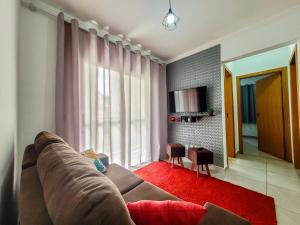 - un salon avec un canapé brun et un tapis rouge dans l'établissement Bem no CENTRO com cozinha completa, varanda e garagem, à Poços de Caldas