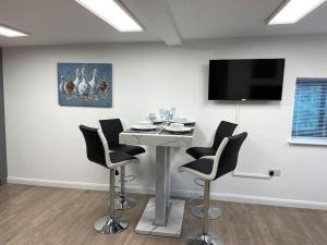 a room with a table with chairs and a flat screen tv at 1 bedroom guesthouse including parking on premises in Braintree