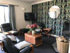 a living room with furniture and a tv and a mirror at Woodbank Road Escape in Hanmer Springs