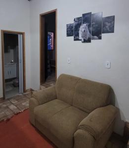un sofá en una sala de estar con fotos en la pared en Chalé Até que Enfim, en Conceição da Ibitipoca