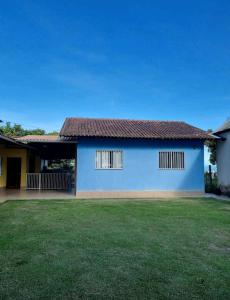 a blue house with a green lawn in front of it at Casa do Renato in Anchieta
