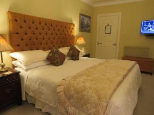 a bedroom with a large bed with a large headboard at Brook Manor Lodge in Tralee