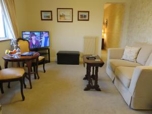 uma sala de estar com um sofá, uma mesa e uma televisão em Brook Manor Lodge em Tralee