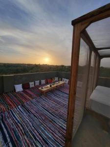 einen Balkon mit einem Tisch und Stühlen auf einem Teppich in der Unterkunft WAFLA in Siwa