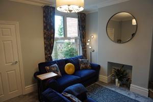 a living room with a blue couch and a mirror at Love Lane Villa in Lincoln