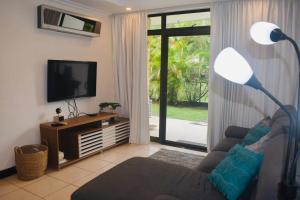 een woonkamer met een bank en een flatscreen-tv bij Country Club Condo in Río Oro