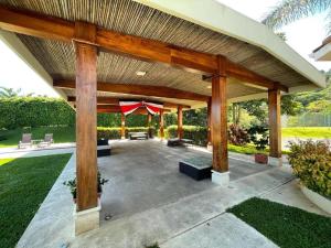 een groot houten paviljoen in een tuin met gras bij Country Club Condo in Río Oro
