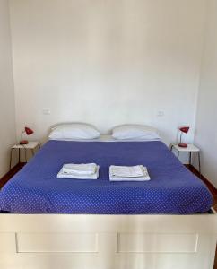 a bedroom with a blue bed with two towels on it at Agriturismo L'Ulivo E Il Mare in Moneglia