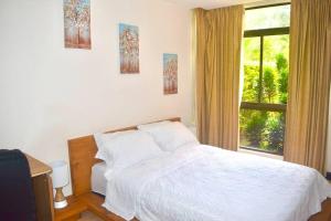 een slaapkamer met een wit bed en een raam bij Country Club Condo in Río Oro