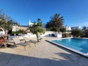 a swimming pool with lounge chairs next to a resort at La Casa d'Olhão in Quelfes