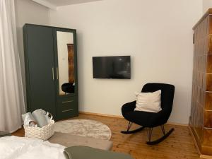 a living room with a chair and a mirror at NOER apartman in Vecsés