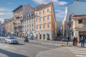 a city street with buildings and a car on the road at Blake, attico centrale con parcheggio a Trieste in Trieste
