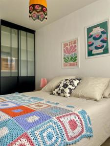 a bedroom with a bed with a colorful quilt on it at Le Cocon Art Déco in Caluire-et-Cuire