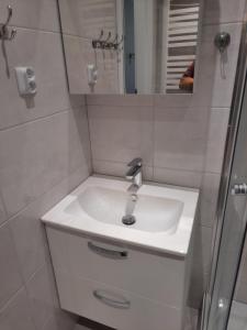 une salle de bain blanche avec un lavabo et un miroir dans l'établissement Barbara Ustroń, à Ustroń