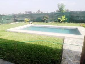a swimming pool with a hose in the grass at Casa de campo con piscina en chincha in Ronceros Bajo