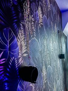 a wall with a chain and a wallpaper with leaves at Love Escape in Nemours