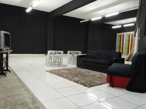 ein Wohnzimmer mit einem Sofa, Stühlen und einem TV in der Unterkunft ParkFlat in Sorocaba