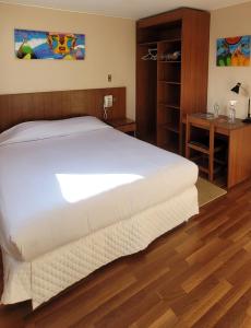 a bedroom with a large white bed and a desk at Hotel Madrid in La Paz