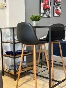 uma mesa com duas cadeiras pretas e uma planta sobre ela em Estudio con encanto en Jávea em Aduanas