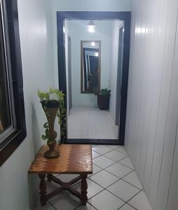 a hallway with a mirror and a table with a vase at Pousada Souza Familiar in Porto Velho