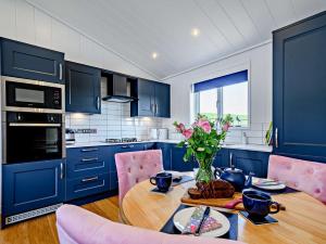 una cocina con armarios azules y una mesa de madera con flores en 2 bed in Castle Douglas 77837 en Auchencairn