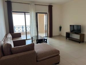sala de estar con sofá y TV en E13 Samarah Resort Apartment, en Sowayma