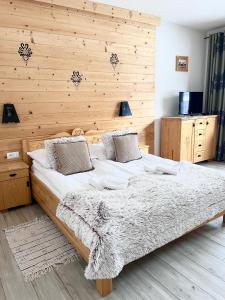 sypialnia z dużym łóżkiem i drewnianą ścianą w obiekcie Willa Kosówka - Apartamenty i pokoje w Zakopanem
