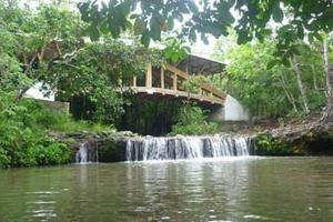 a bridge over a waterfall next to a river at Fresca casa completa Monterrey casanare in Monterrey