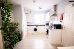 a kitchen with white cabinets and a dishwasher at Dunstable Rd Modern Ensuites by Pioneer Living in Luton