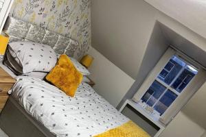 uma pequena cama com uma almofada amarela ao lado de uma janela em Harris Apartment em Montrose