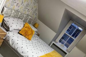 a small bed with a yellow pillow next to a window at Harris Apartment in Montrose