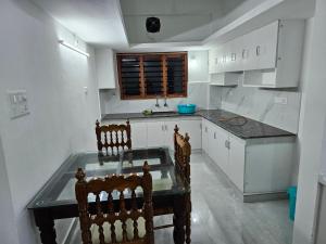 een keuken met een glazen tafel en 2 stoelen bij ZEAL HOMES And Apartments Koothattukulam in Kuttāttukulam