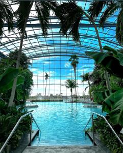 a swimming pool in a building with a glass ceiling at Mona Apartment Taxi#Airport #PARKING#BUCHAREST#THERME in Otopeni