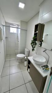 a white bathroom with a toilet and a sink at Condomínio Vista Atlântico - Apartamento Novo - Próximo à Praia - Vista Mar - Área de Lazer in Itapema